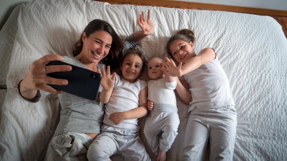 A mom taking a selfie of her and her kids in bed