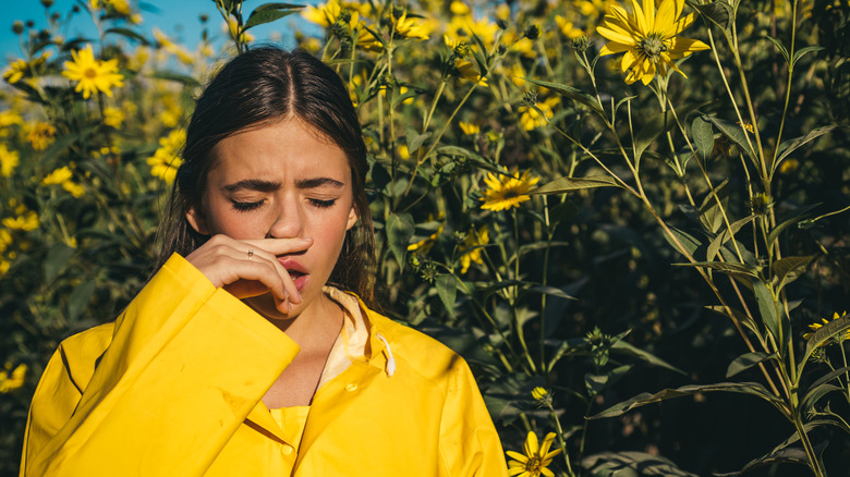 Woman sneezing near flowers