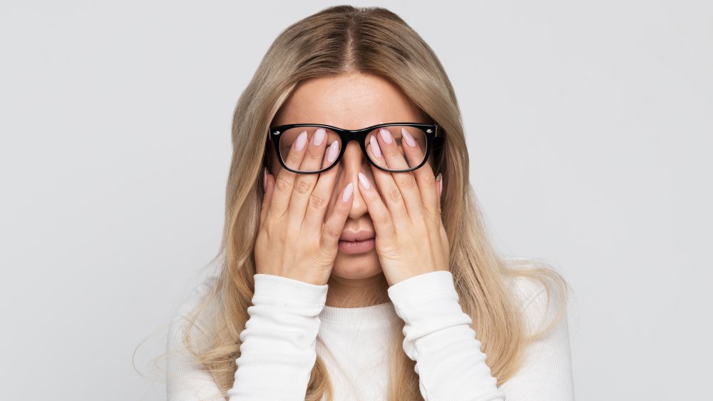 woman with glasses rubbing eyes