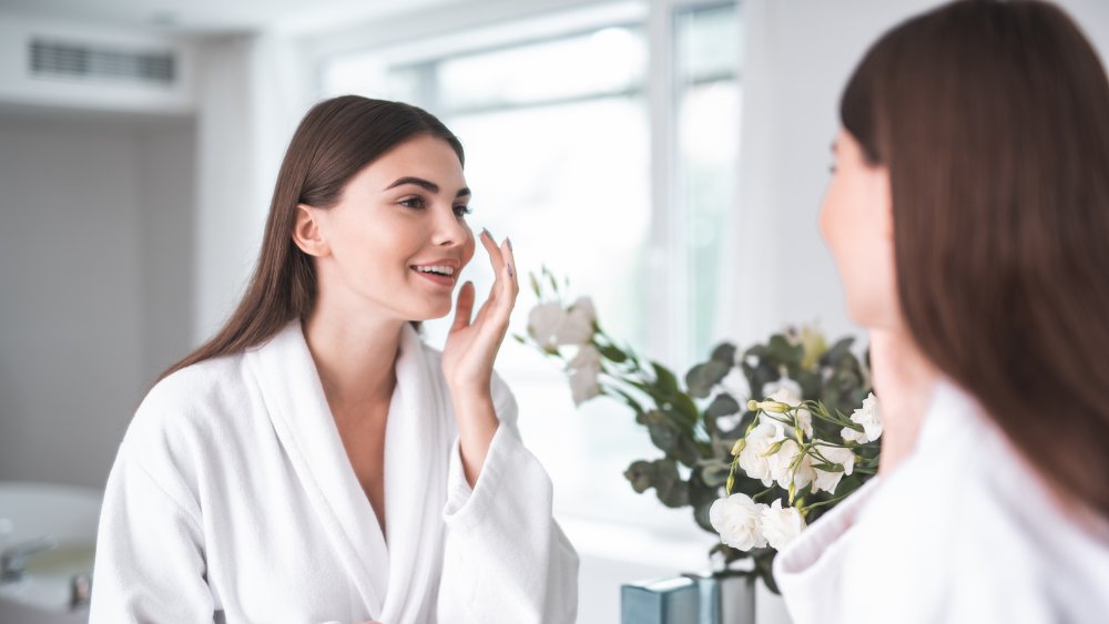 woman looking at her skin in the mirror