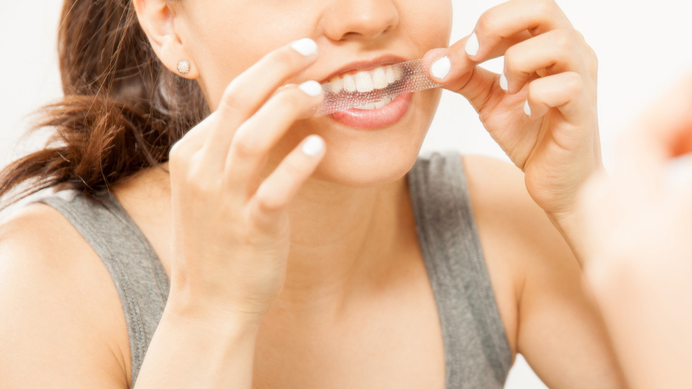 A woman applying whitening strips 