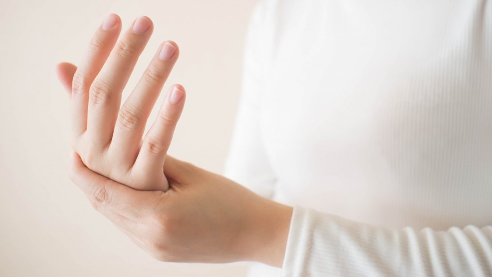 A woman wearing white holding her hands together