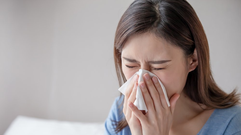 A woman holding a tissue to her face