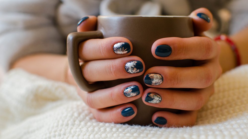 A woman's manicured hands holding a mug