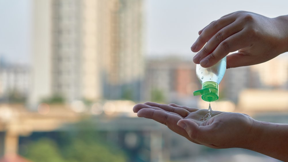 Hands applying hand sanitizer with a city background