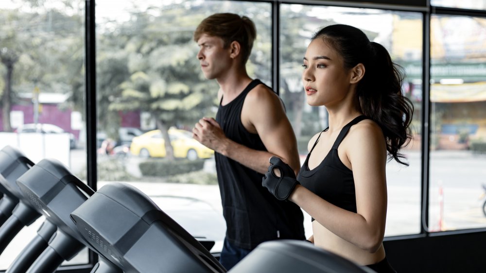 A woman and a man walking on treadmills