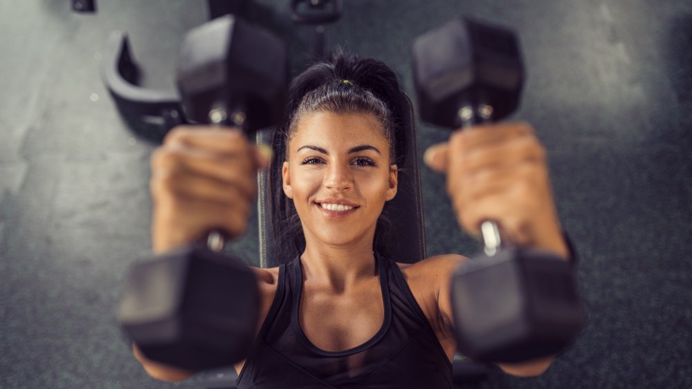 A woman lifting dumbbells from above