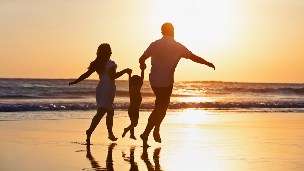 A family walking on a beach at sunset