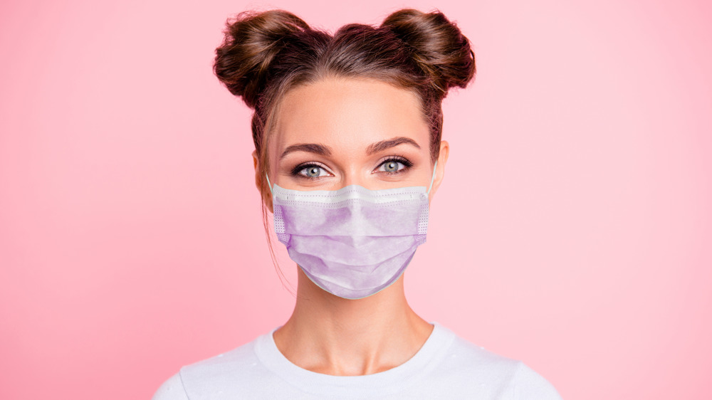 A woman is wearing makeup and a surgical mask.