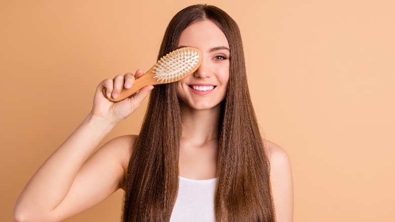 woman holding brush while smiling