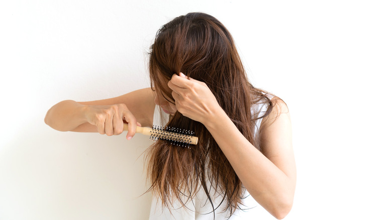 woman detangling hair with brush