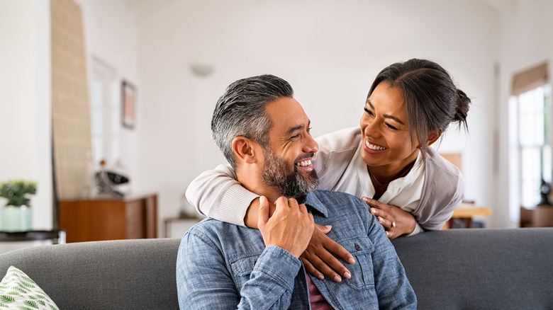 Couple smiling as man sits on couch