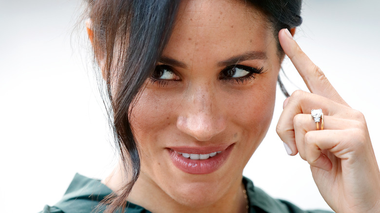 Meghan Markle holding her wedding ring up to her face