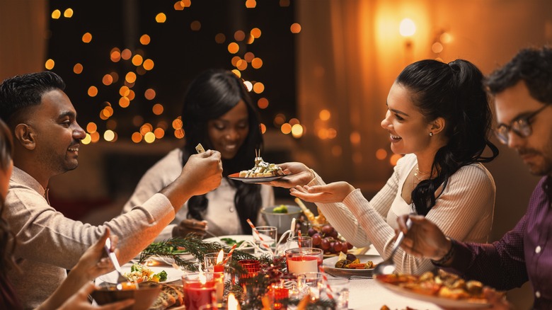 People eating dinner with Christmas lights behind them