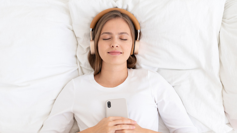 A woman in bed with headphones on 