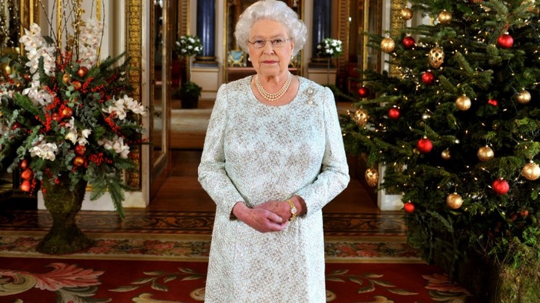 Queen Elizabeth II standing in front of a Christmas tree