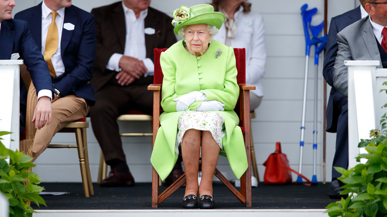 Queen Elizabeth II sitting wearing green dress and hat