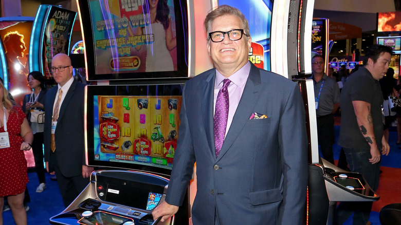 drew carey posing in front of a slot machine