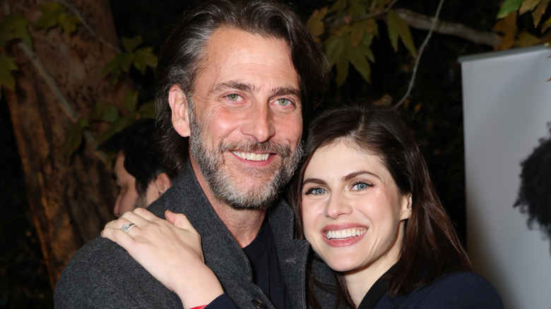 Andrew Form and Alexandra Daddario smiling for the camera outdoors