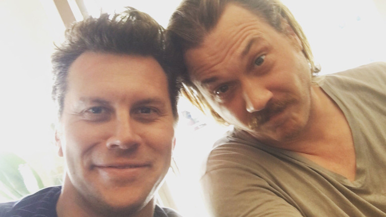 Hayes MacArthur and Scott MacArthur touching heads looking forward