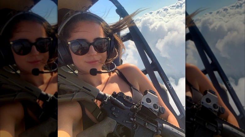 Ashley St. Clair in airplane with gun across chest