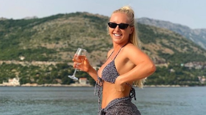 Courtney Veale posing with a wine glass near water