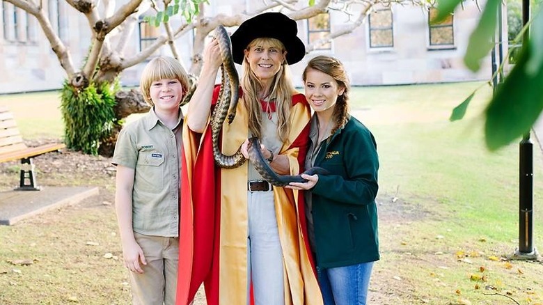 Terri with her kids holding a snake in her graduation robes