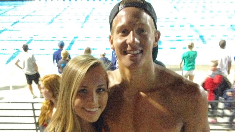 Meghan and Caeleb Dressel posing in front of a swimming pool