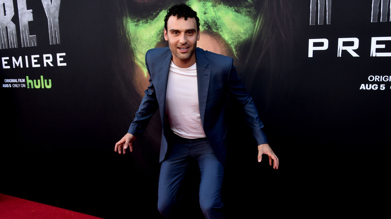 Dane DiLiegro posing in front of Prey poster on red carpet