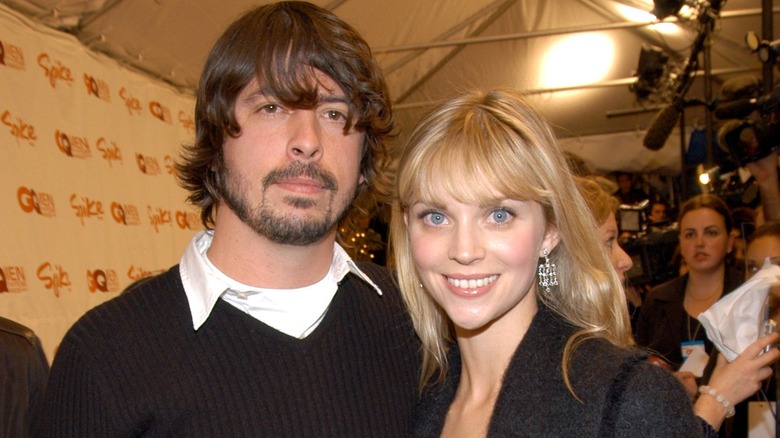 Jordyn Blum with blonde hair and bangs in a gray coat with Dave Grohl in white shirt and dark sweater