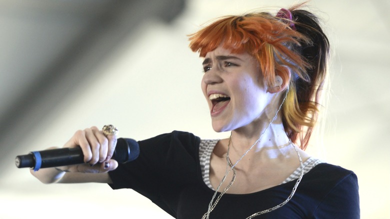 Grimes with orange hair singing into a microphone