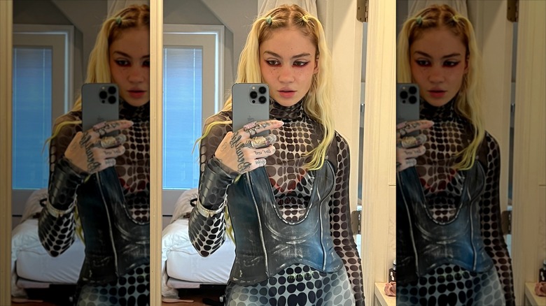 A mirror selfie of Grimes in a polka dot bodysuit, her hair in pigtails and freckles drawn on her face