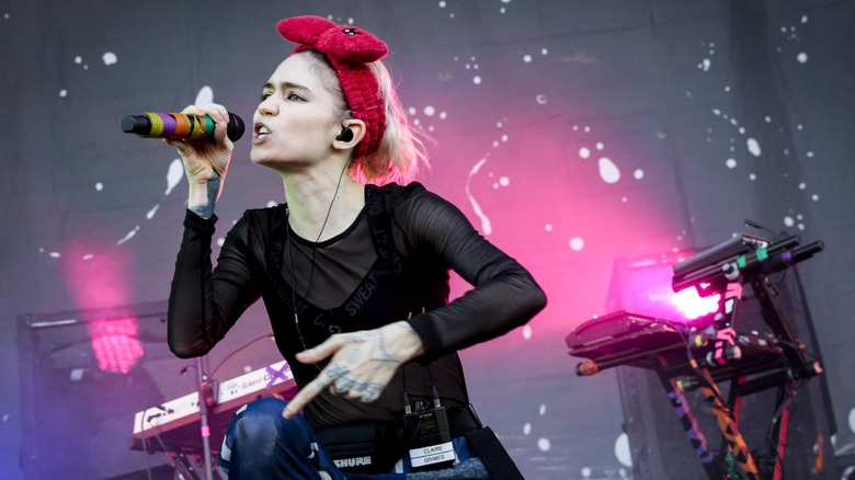 Grimes wearing a big red bow headband and performing onstage