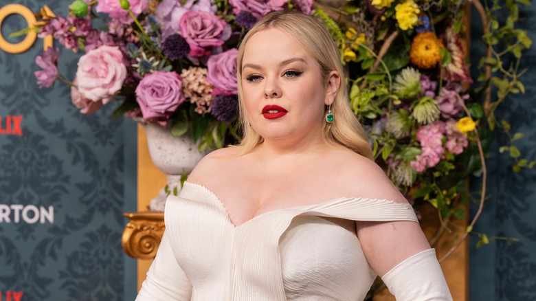 Nicola Coughlan posing for photos in a white dress with red lipstick