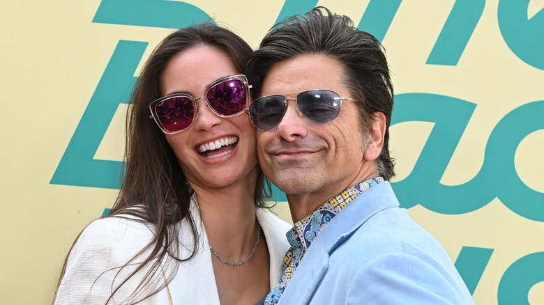 John Stamos and Caitlin McHugh Stamos smile on red carpet in sunglasses