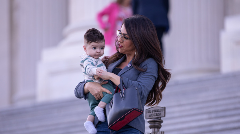 Lauren Boebert is walking down the House steps while holding her infant grandson