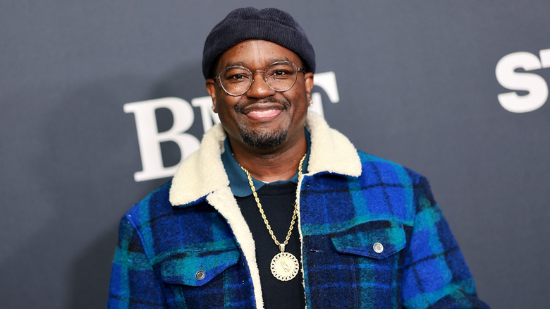 Lil Rel Howery wearing glasses, knit cap, and plaid coat