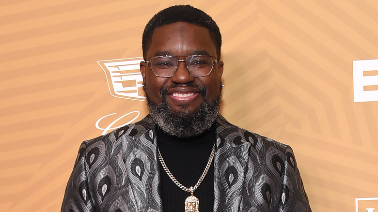 Lil Rel Howery smiling in glasses and silver patterned suit