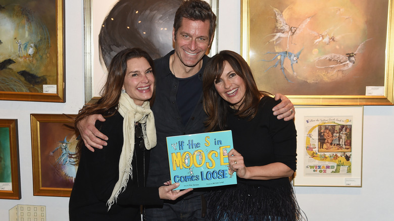 Peter Hermann and Mariska Hargitay smiling while holding his book