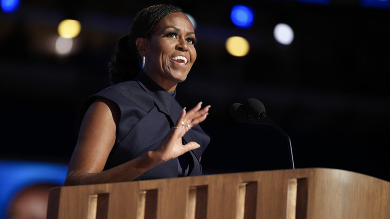 Michelle Obama speaking to a crowd in a black outfit