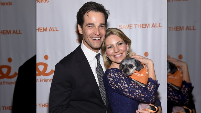 Rob and Eryn Marciano posing with a small dog 