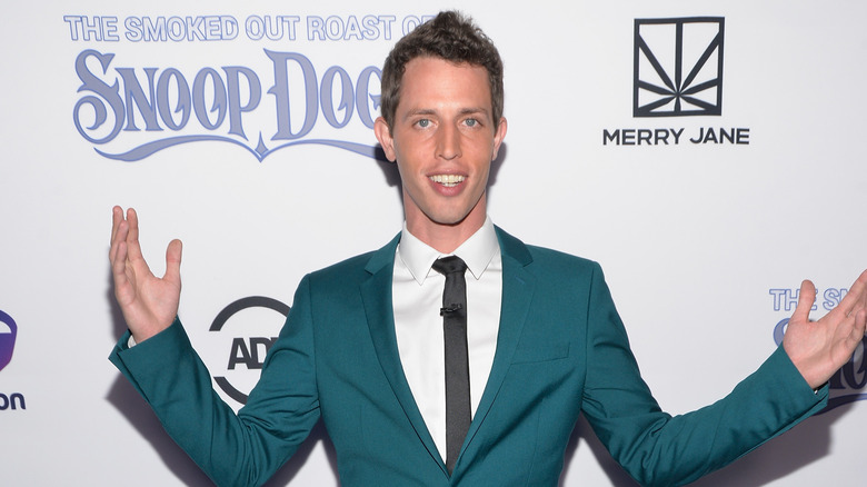 Tony Hinchcliffe posing with open arms in an aqua suit