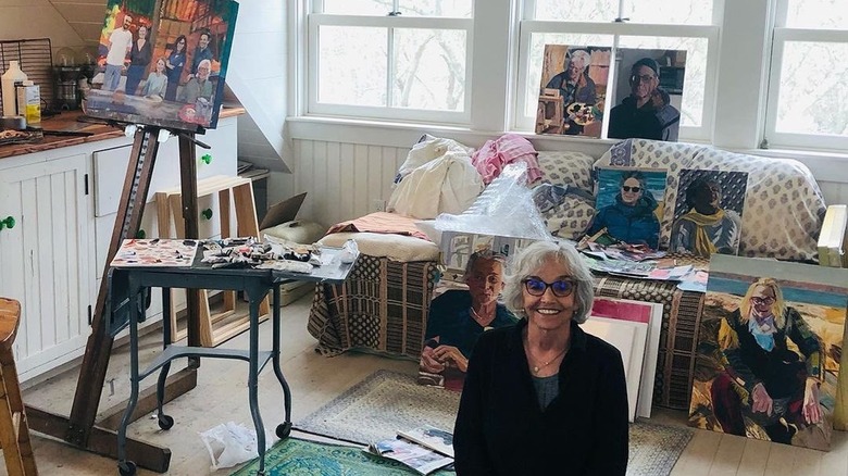 Brooke Adams sitting in her art studio, surrounded by paintings