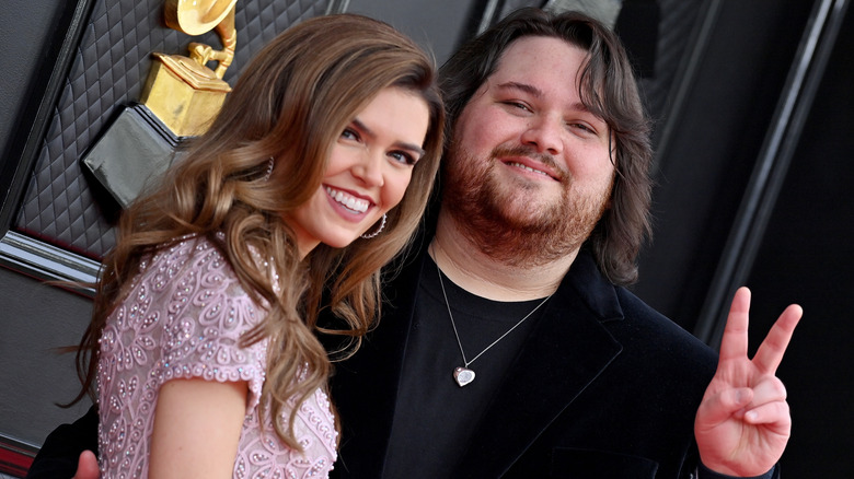 Andraia Allsop smiling with Wolfgang Van Halen doing peace sign on Grammys red carpet