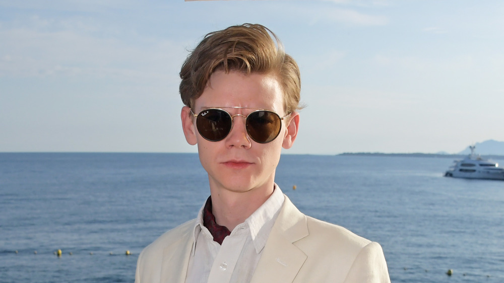 Thomas Brodie-Sangster wearing sunglasses, standing by the sea 