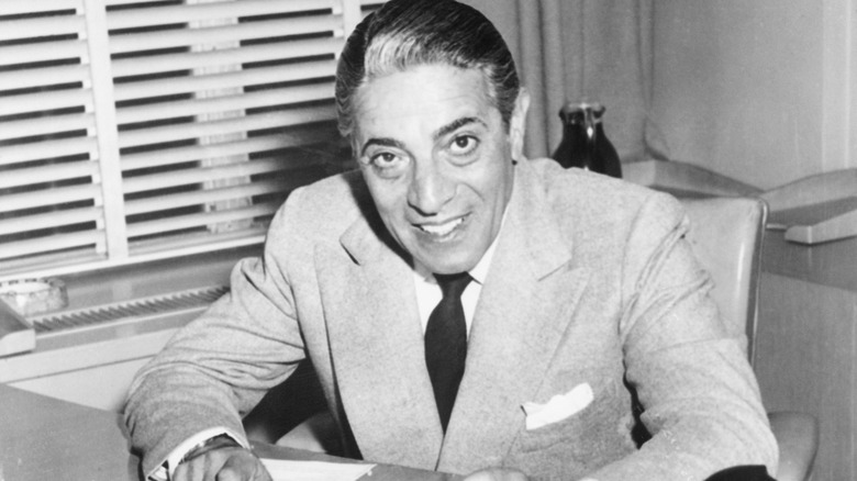 Aristotle Onassis sitting behind a desk