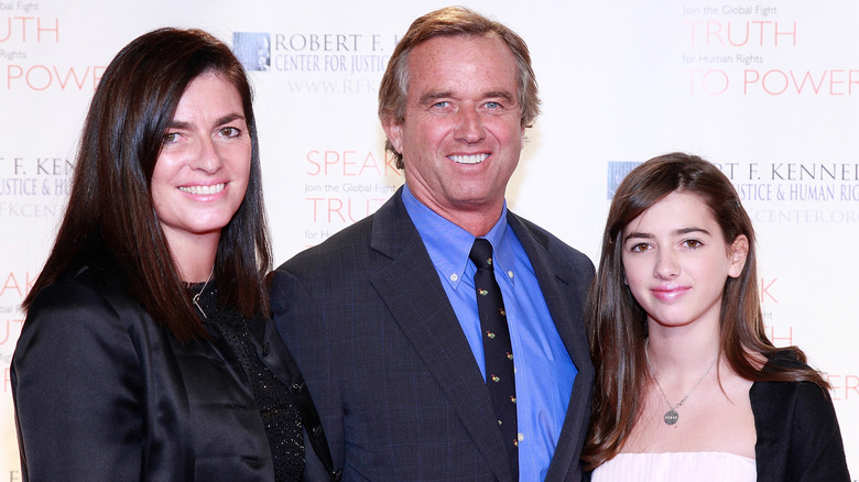 Mary Richardson and RFK Jr. smiling with their daughter Kyra on step-and-repeat