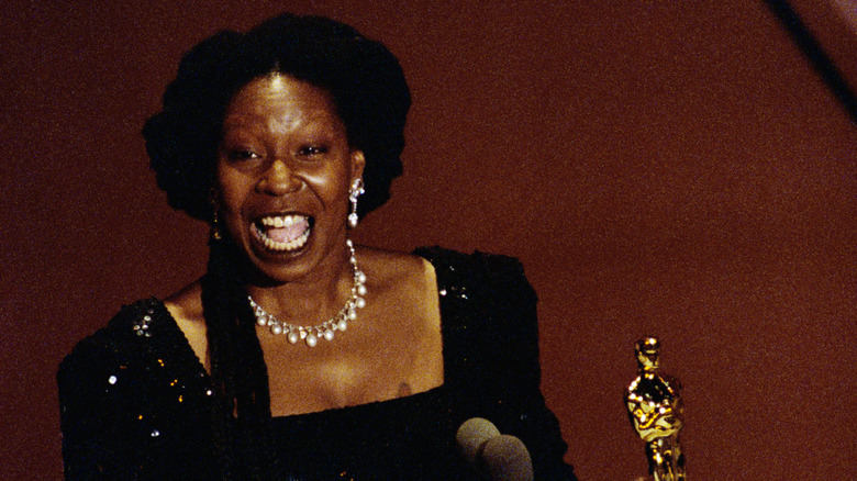 whoopi goldberg holding oscars statue.