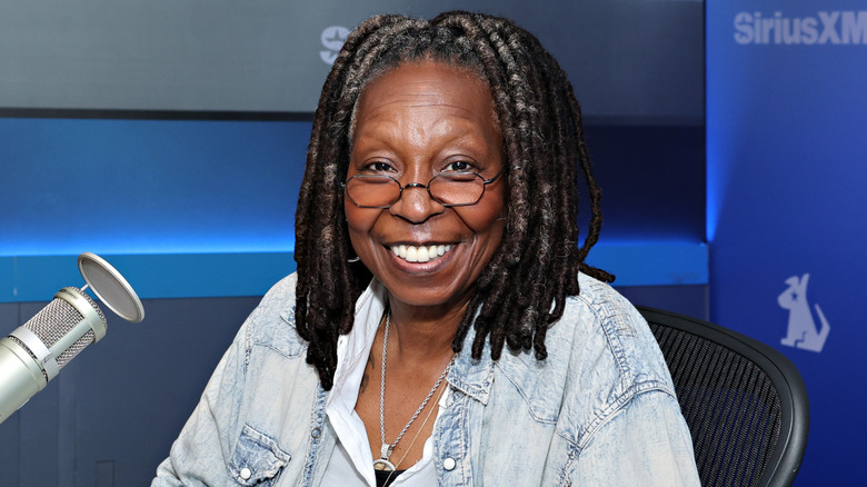 Whoopi Goldberg next to a mic, smiling