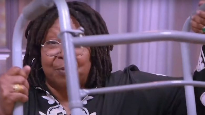 Whoopi Goldberg holding up her walker